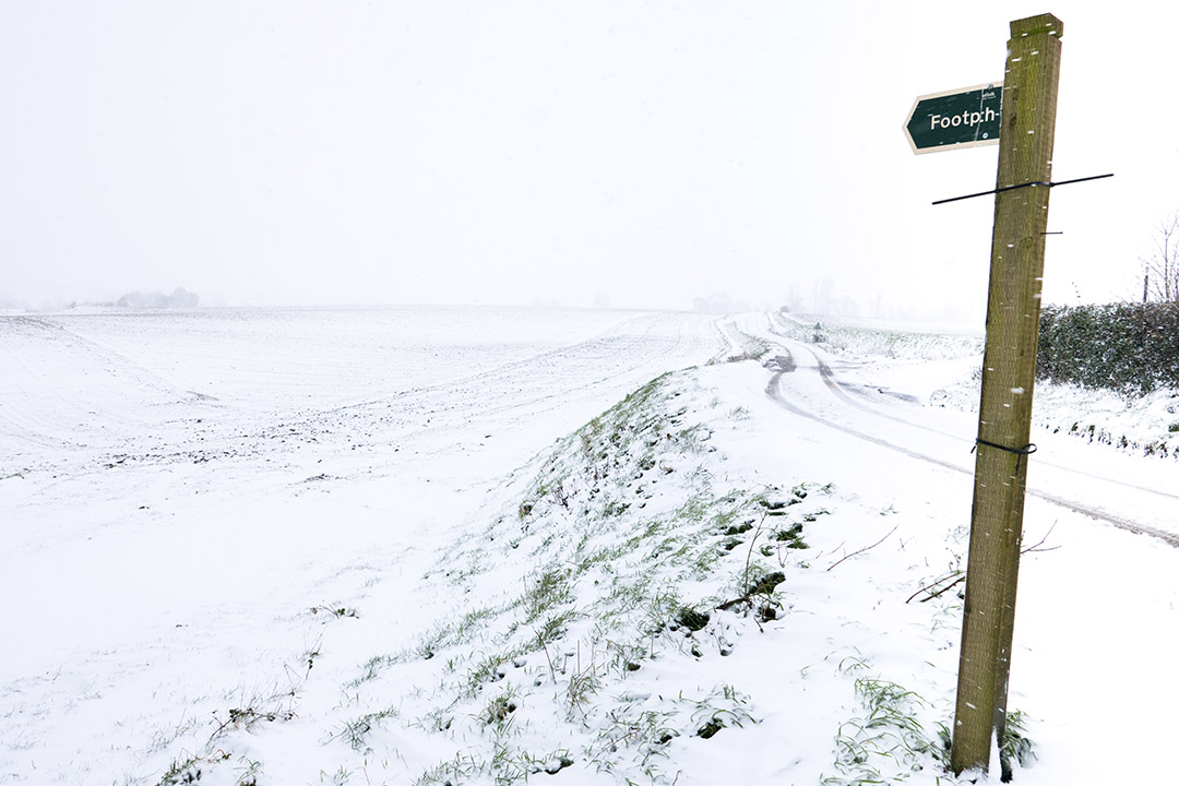 Snow covered fields with footpath sign