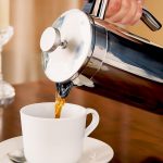 Pouring a cafetiere of coffee into a white cup