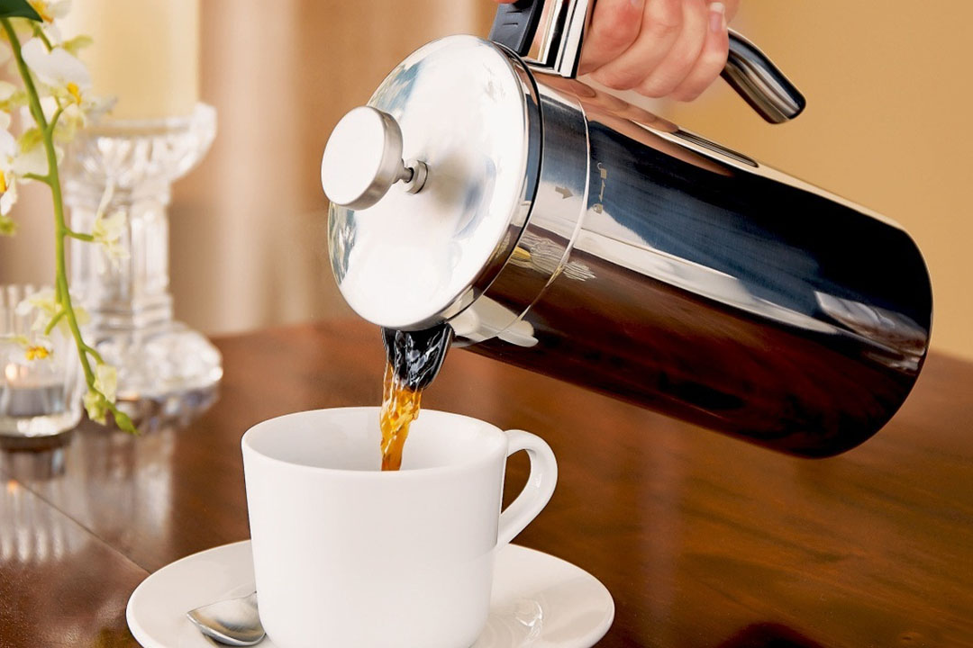 Pouring a cafetiere of coffee into a white cup